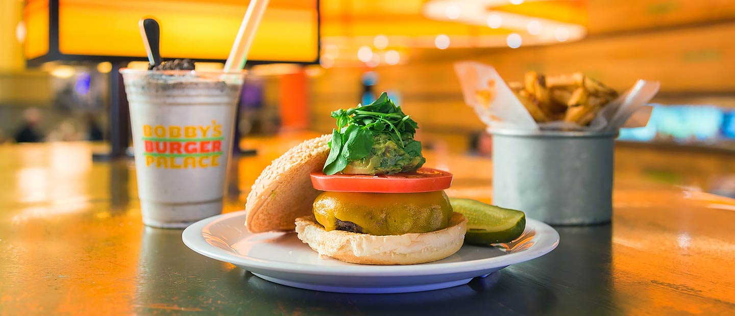 Burger with guacamole and cheese and a shake in the background