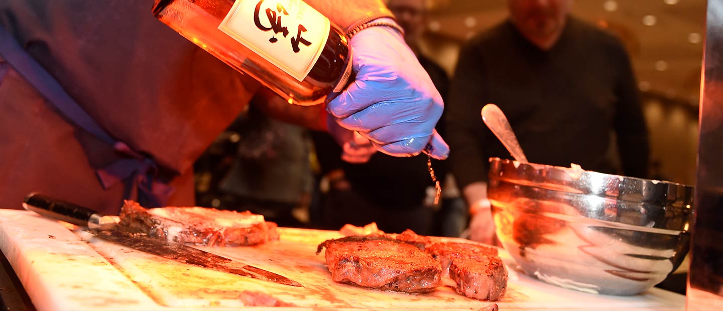 Chef pouring whiskey on steaks